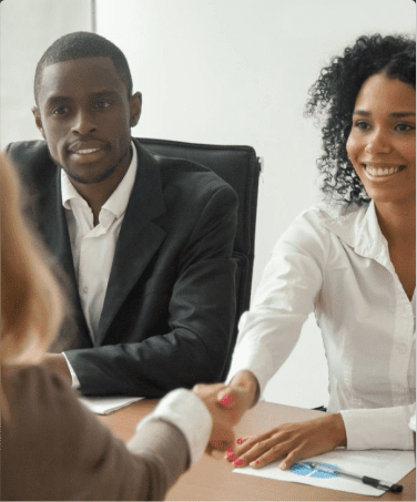 A man and woman shaking hands over a table.