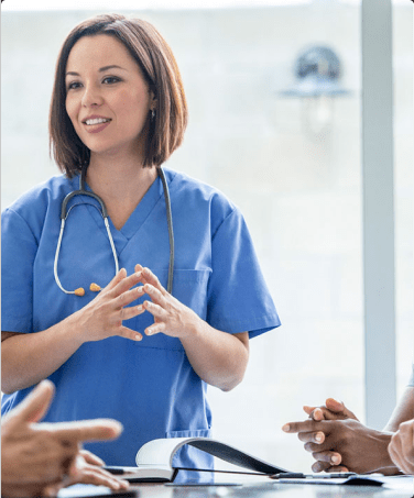 A woman in scrubs talking to people.