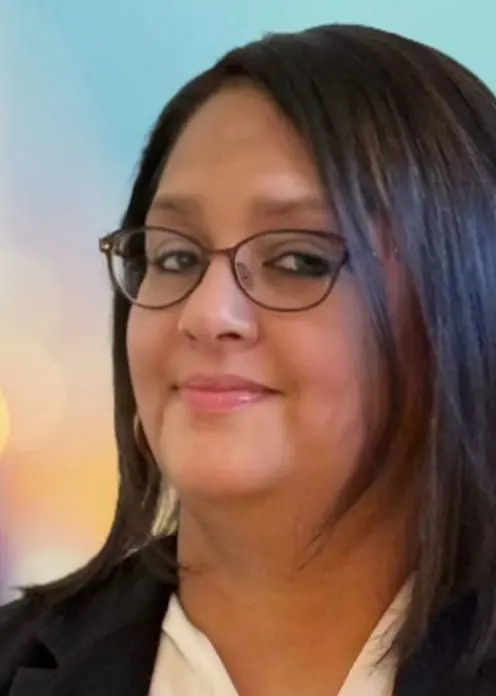 A woman with glasses is smiling for the camera.