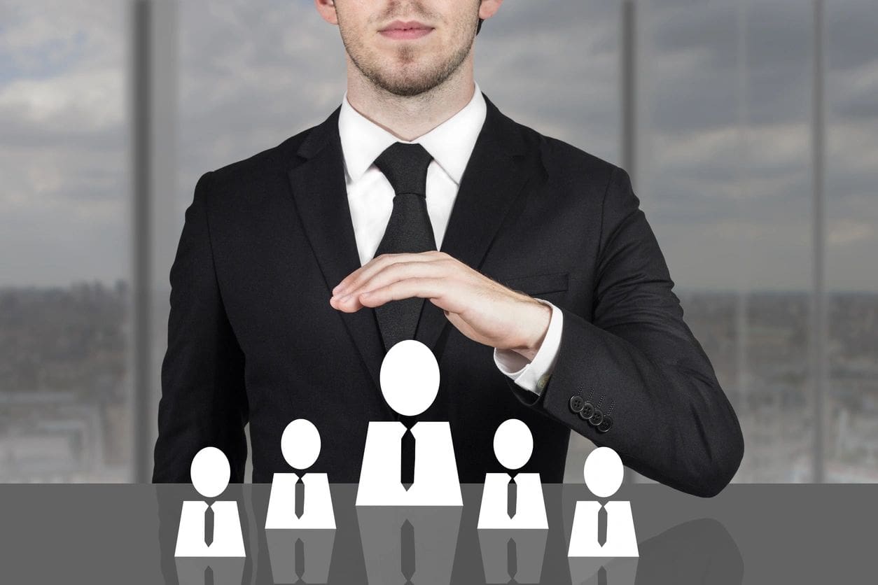 A man in a suit and tie standing behind some people.